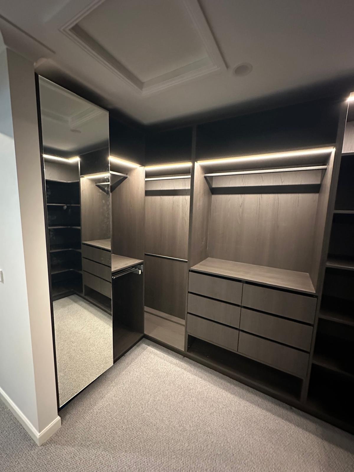 Walk-in robe mirror and hanging bays illuminated with integrated LED strip lighting