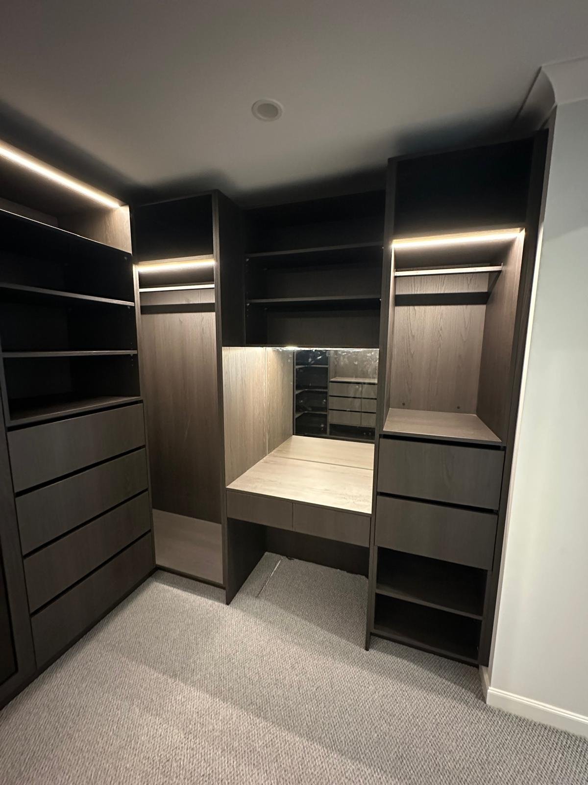 Custom walk-in robe vanity and shelving with warm integrated lighting
